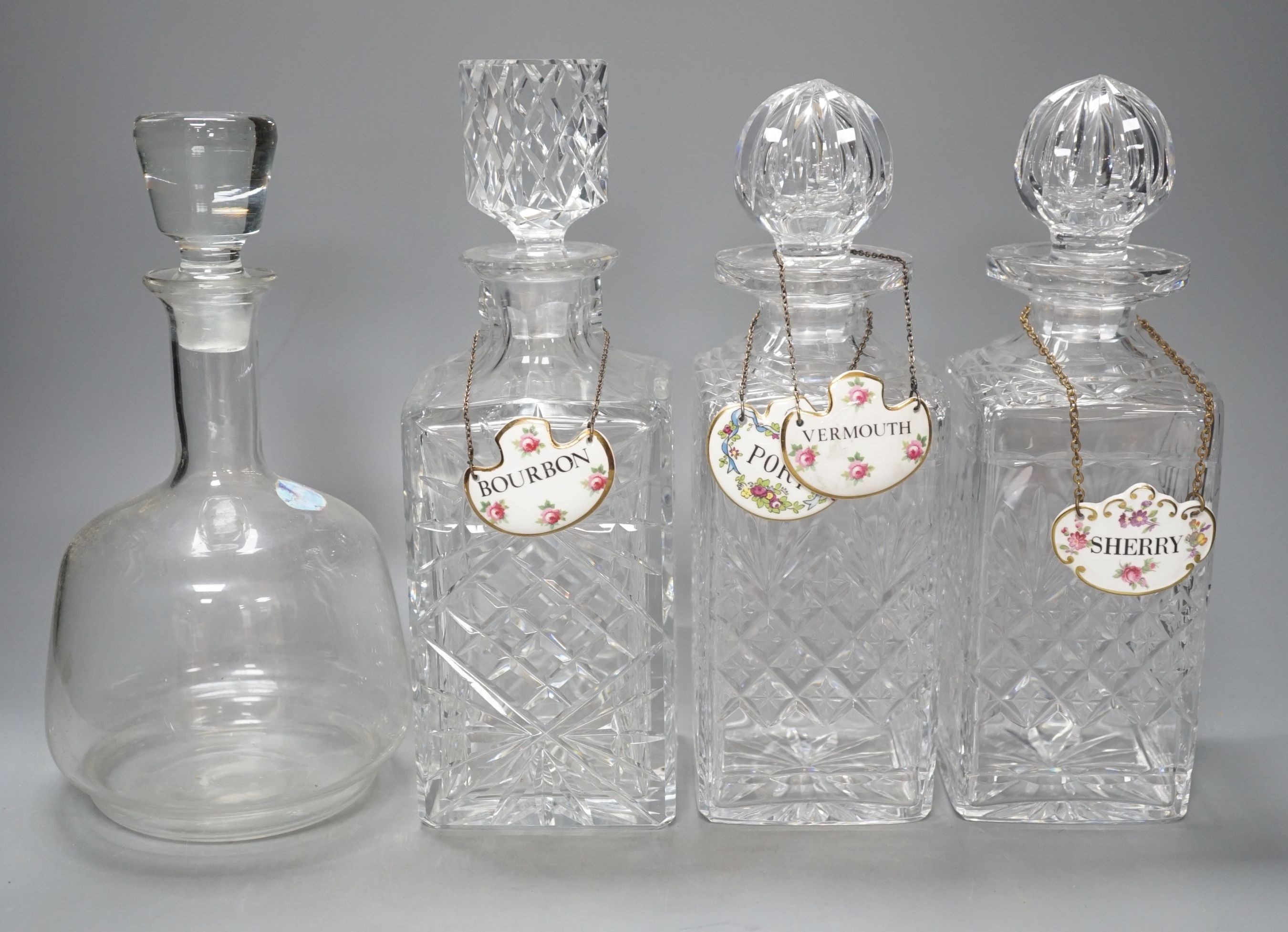 A pair of glass decanters, another similar and a mallet decanter and four decanter labels, Pair 27 cms high.